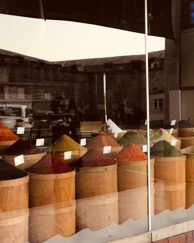 Wooden barrels filled with colorful spices on display in a market window.